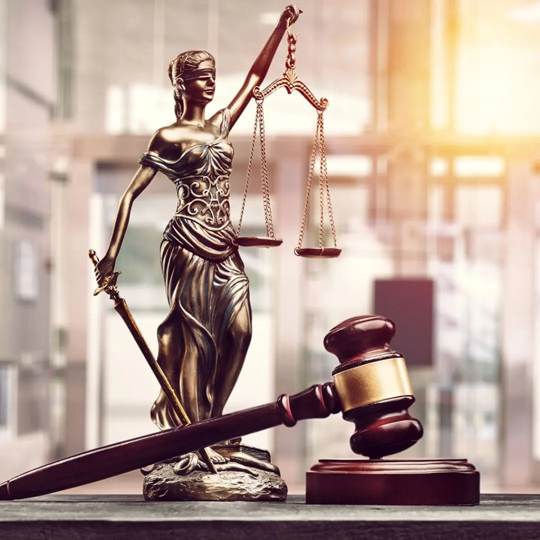 Lady justice statue with scales and a gavel on a desk