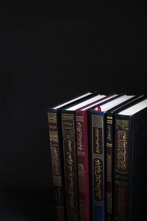 Spines of Arabic legal books against a black background