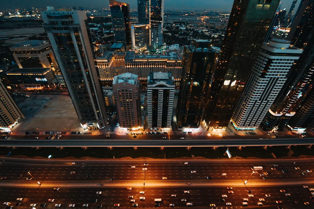 Aerial night view of a city skyline with lit towers and infrastructure