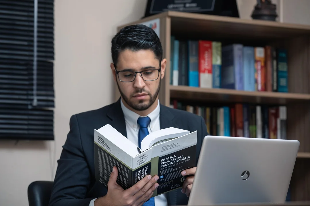 Lawyer reading a legal textbook at a laptop in front of a bookcase
