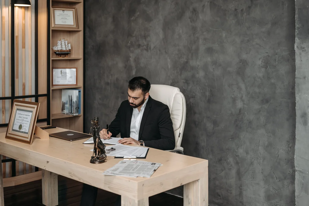 Lawyer signing documents beside a certificate in an Al Jabal Law Firm office