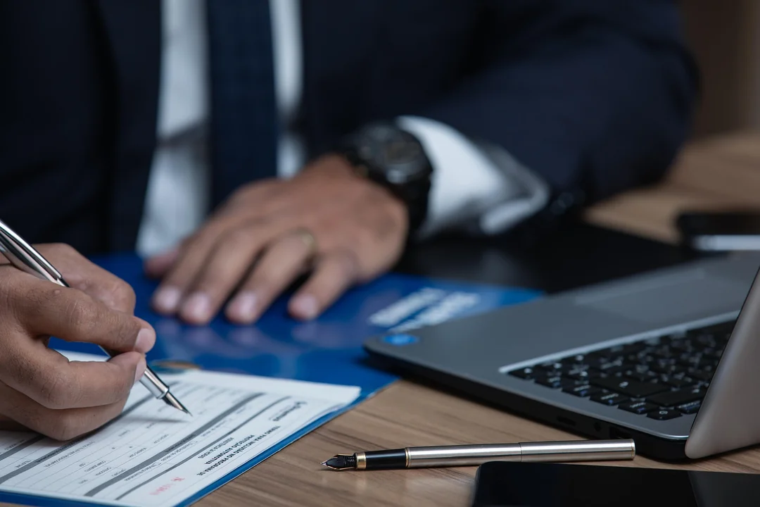 Lawyer signing a legal document beside a laptop, representing corporate and commercial law in Iraq